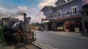 Un treno sui binari, con un edificio con la scritta "HOTEL HOOSQUEEN" sullo sfondo.