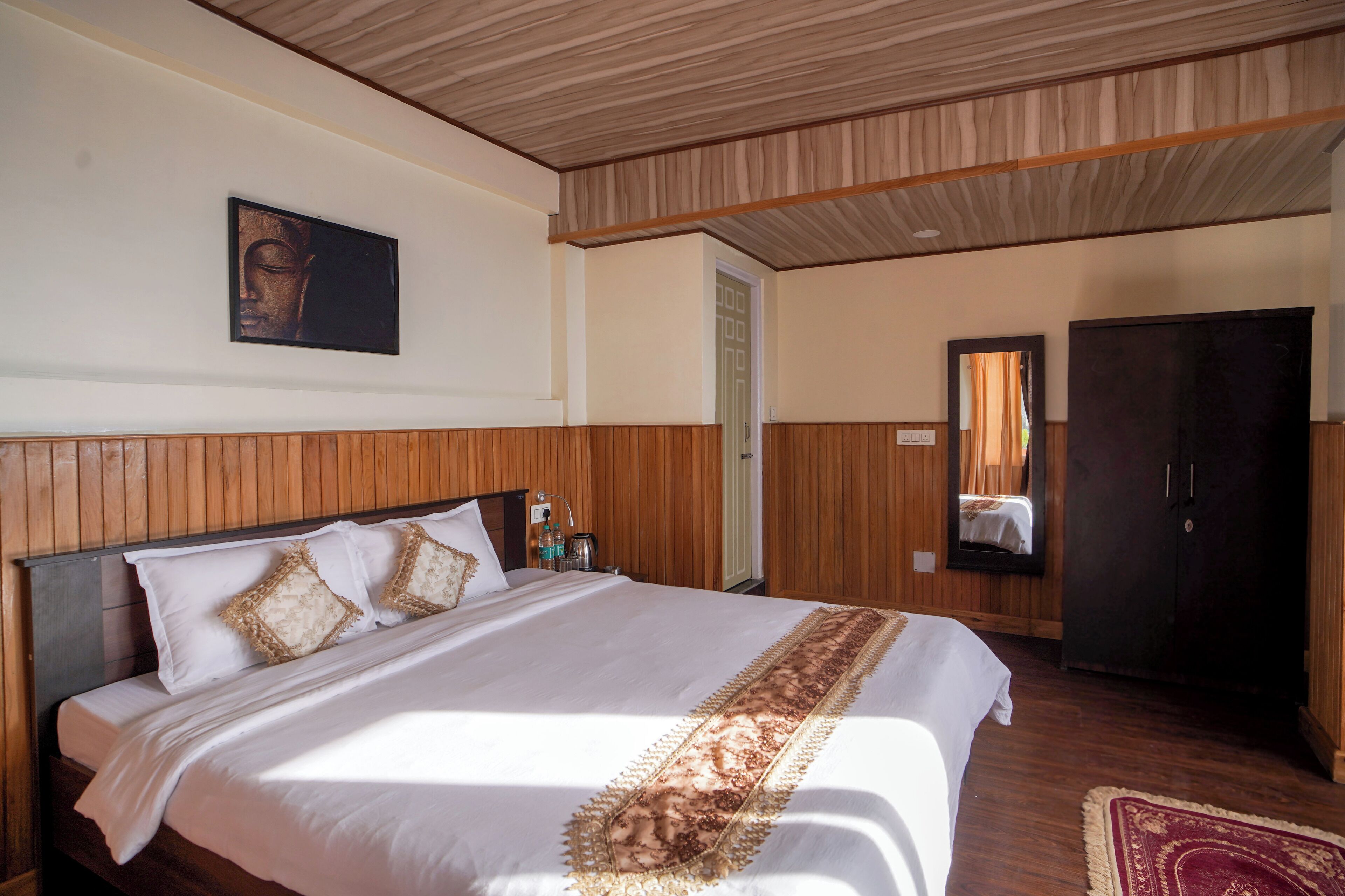 A hotel room with a wooden headboard, a large bed with white bedding, a wooden ceiling, and a mirror on the wall.