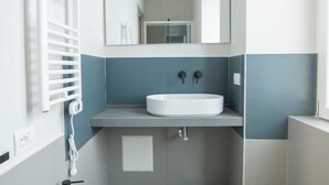 Een moderne badkamer met een wit wastafel, een spiegel en een handdoekhouder.