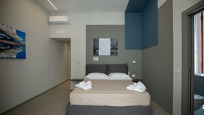 Een moderne slaapkamer met een groot bed, een plafondventilator en een schilderij aan de muur.