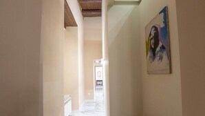 Un couloir doté d’un sol en marbre, de murs blancs et d’un tableau accroché sur le côté droit.