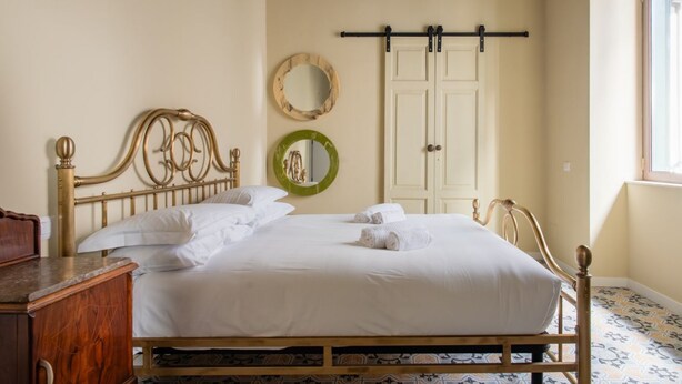 A neatly made bed with white linens and towels, a wooden headboard, and a wooden dresser to the left. - Speranzella 2 By Dimorra (NAPOLI)