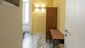 A hallway with a marble floor, a wooden bench, and a wall-mounted light fixture. - Ventaglieri 74 Majestic Room 2 By Dimorra (NAPOLI)