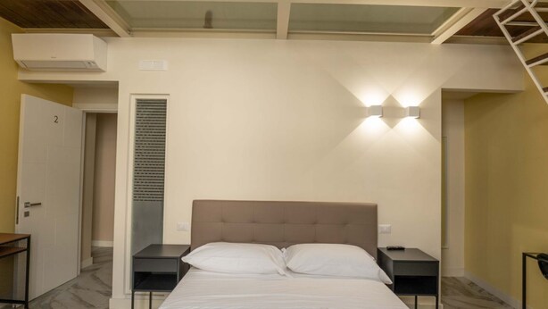 A bedroom with a bed, two bedside tables, a wardrobe, and a skylight. - Ventaglieri 74 Majestic Room 2 By Dimorra (NAPOLI)