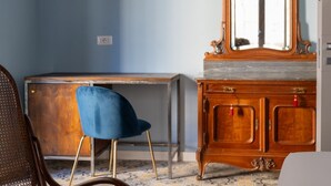 Habitació amb un armari de fusta, una cadira blava, un escriptori i un mirall.