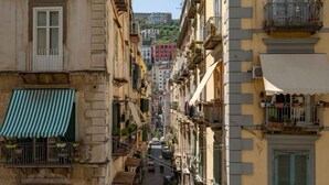 Una calle estrecha bordeada por edificios de varios pisos con balcones, algunos con plantas.