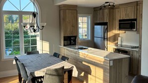 Une cuisine moderne avec des meubles en bois, un réfrigérateur en acier inoxydable et un four à micro-ondes encastré.