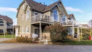 Une maison à deux étages avec un balcon, une véranda et un garage.