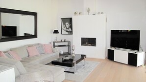 En moderne stue med en grå sofa, et sofabord, et fjernsyn og en pejs.