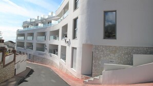A modern multi-story building with balconies, a stone facade, and a staircase leading to an entrance. - Holiday apartment in Inbisa (Mijas)