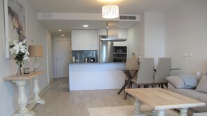 A modern living room with a sofa, a coffee table, and a dining area with chairs. - Holiday apartment in Inbisa (Mijas)