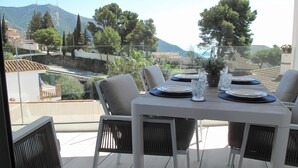 A dining table set for four on a balcony with a view of the sea and mountains. - Holiday apartment in Inbisa (Mijas)