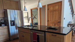 Eine moderne Küche mit einem Edelstahlkühlschrank, einer eingebauten Spüle und Holzschränken.