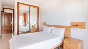 Une chambre d’hôtel moderne avec un grand lit, une tête de lit en bois, des tables de chevet et un miroir.