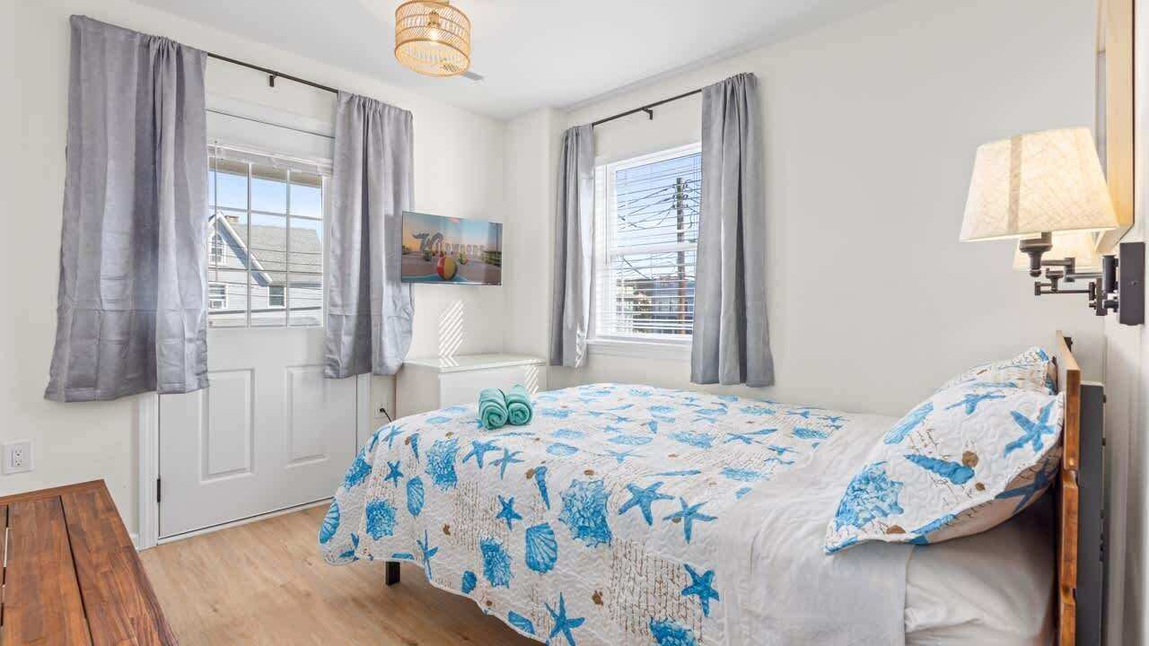 A bedroom with a bed, a bedside table, a lamp, and a window with curtains.