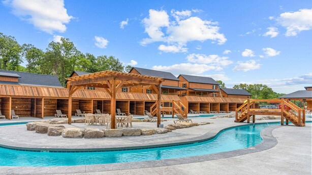 A pool area with wooden structures, lounge chairs, and a clear blue sky. - Resort Cabin Near Branson Attractions & Thunder Ridge (Hollister)