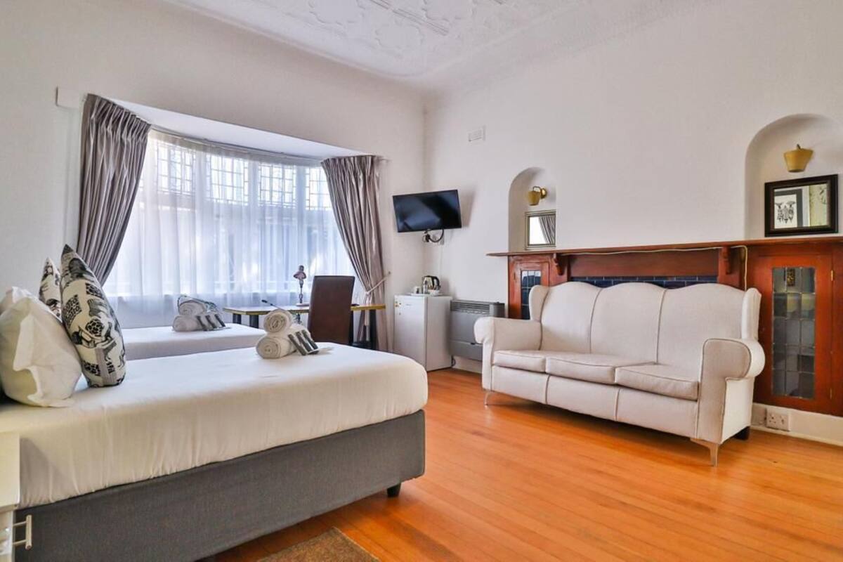 Ein modernes Hotelzimmer mit Bett, einer Couch, einem Fernseher und einem Kamin.