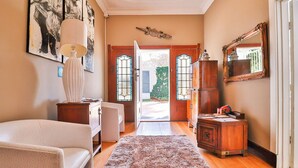 Una habitación con cama, escritorio, silla, lámpara, alfombra, espejo y puerta que da al exterior.