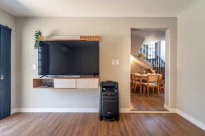A room with a flat-screen TV mounted on the wall, a wooden dining table with chairs, and a suitcase on the floor. - Casa alto padrão com piscina 15 pessoas (Bombinhas)