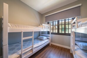 A room with bunk beds, a window with blinds, and a view of buildings outside. - Casa alto padrão com piscina 15 pessoas (Bombinhas)