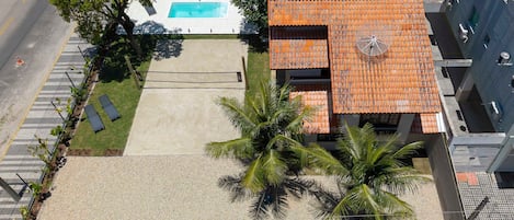 An aerial view of a building with a swimming pool, a covered patio, and a parking area.