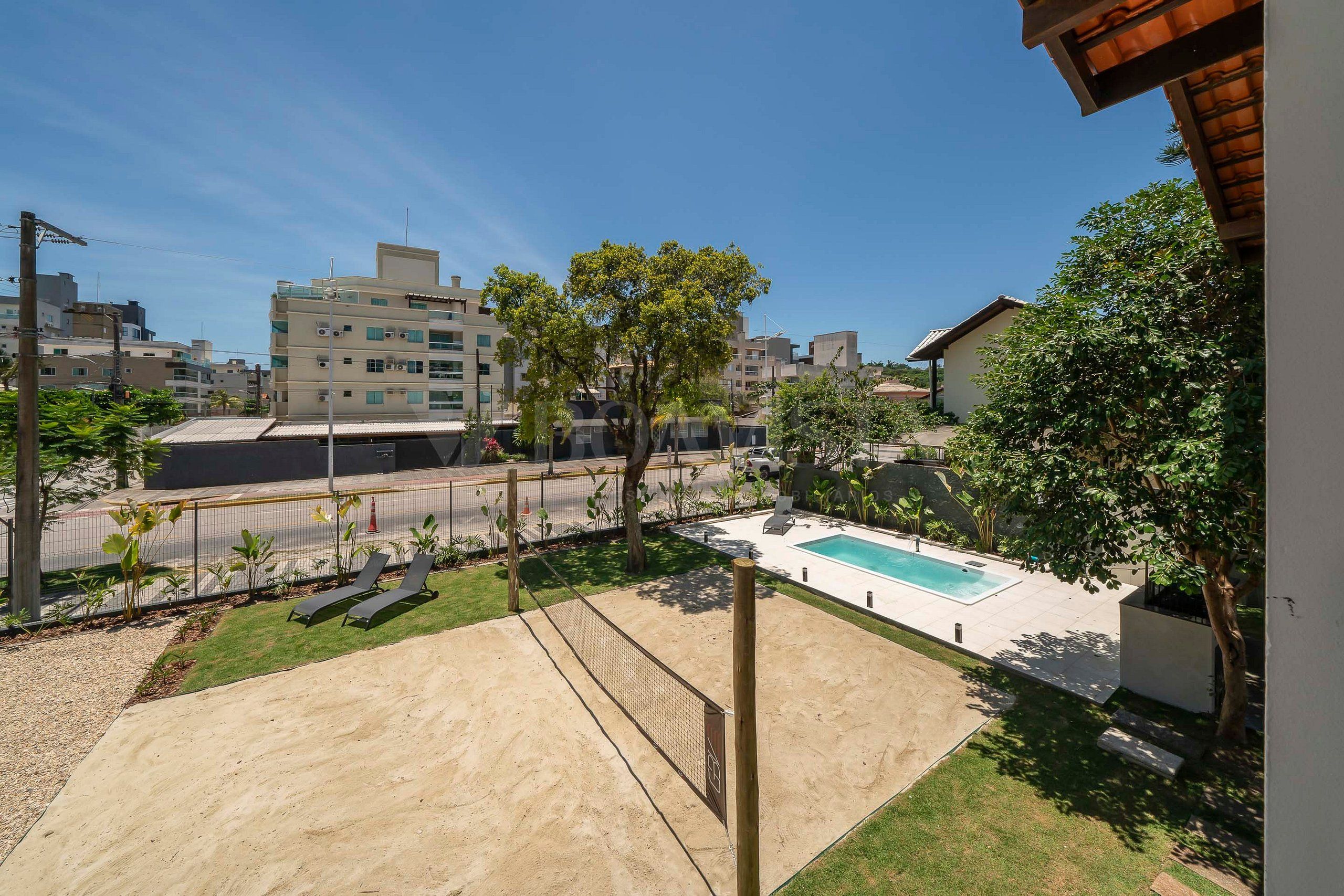 A residential area with a swimming pool, a fenced yard, and buildings in the background.