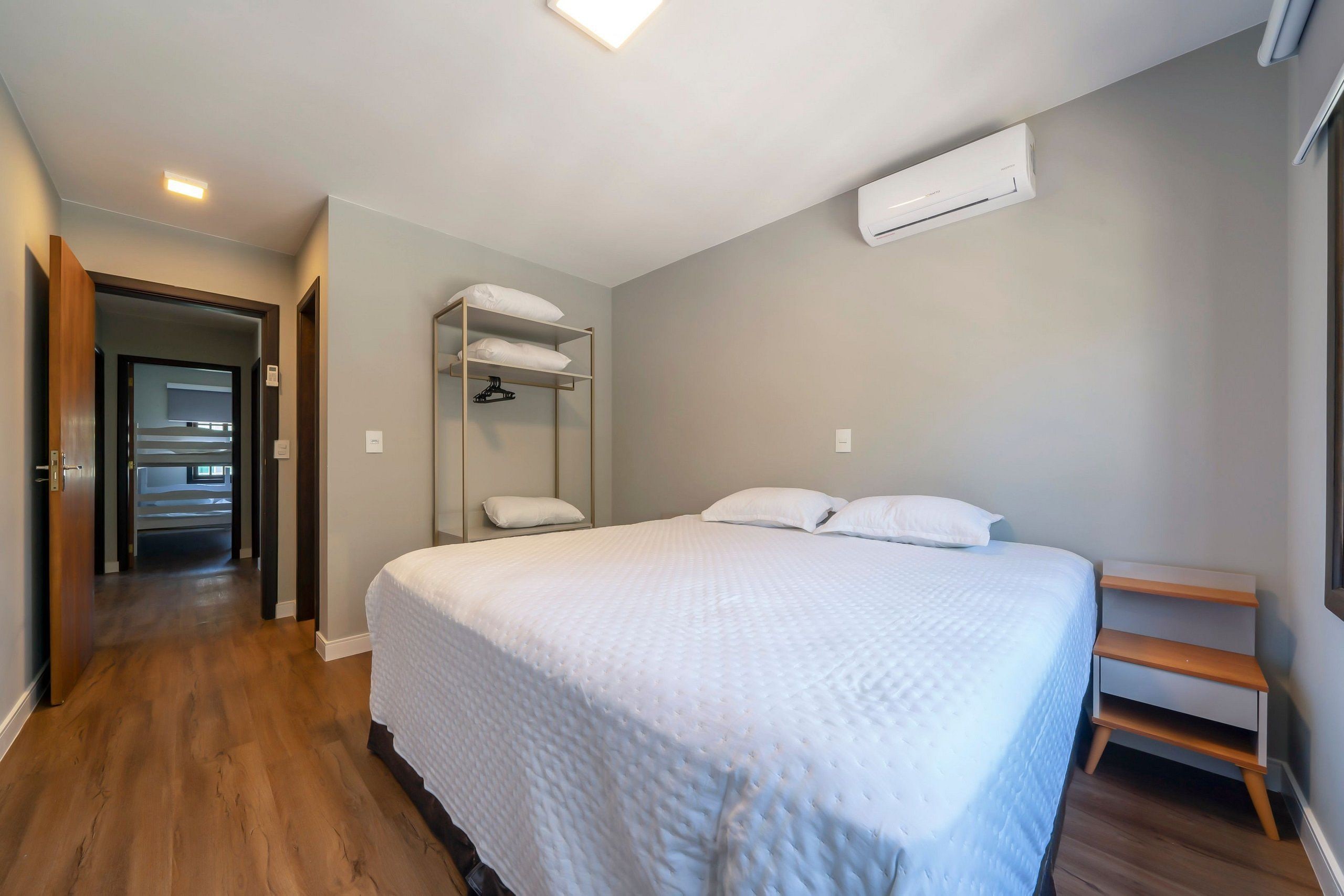 Un dormitorio con una cama grande, suelo de madera, armario empotrado y aire acondicionado instalado en el techo.