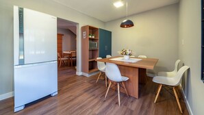 Una cocina moderna con un refrigerador blanco, armarios de madera y un comedor con una mesa de madera y sillas blancas.