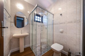 Une salle de bain avec une douche à parois de verre, un lavabo sur colonne et des toilettes.