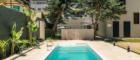 A rectangular swimming pool with a clear blue water, surrounded by a tiled deck.