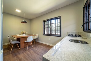 Una cocina moderna con encimera de granito, estufa integrada y ventana con barrotes negros.