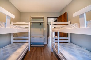 A bunk bed room with a wooden floor, a closet, and a door leading to another room. - Casa alto padrão com piscina 15 pessoas (Bombinhas)