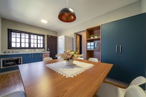 Une cuisine moderne avec une table à manger en bois, des placards intégrés et un luminaire suspendu.