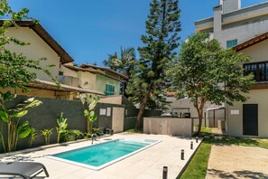Un barrio residencial con piscina, un alto pino y un edificio de techo a dos aguas.