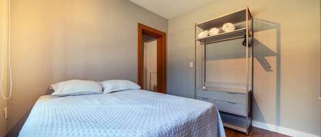 A bedroom with a bed, a wardrobe, and a door leading to another room.