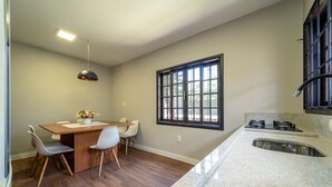Una cucina moderna con un piano di lavoro in granito, un piano cottura integrato e una finestra con inferriate nere.