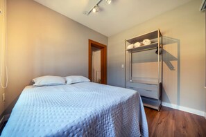 A bedroom with a bed, a wardrobe, and a door leading to another room. - Casa alto padrão com piscina 15 pessoas (Bombinhas)