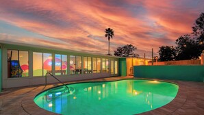 A swimming pool with a curved edge, surrounded by a brick patio.