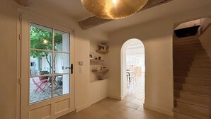 Ein Flur mit Glastür zu einer Terrasse, einer Treppe und einem durch einen Durchgang erreichbaren Küchenbereich.