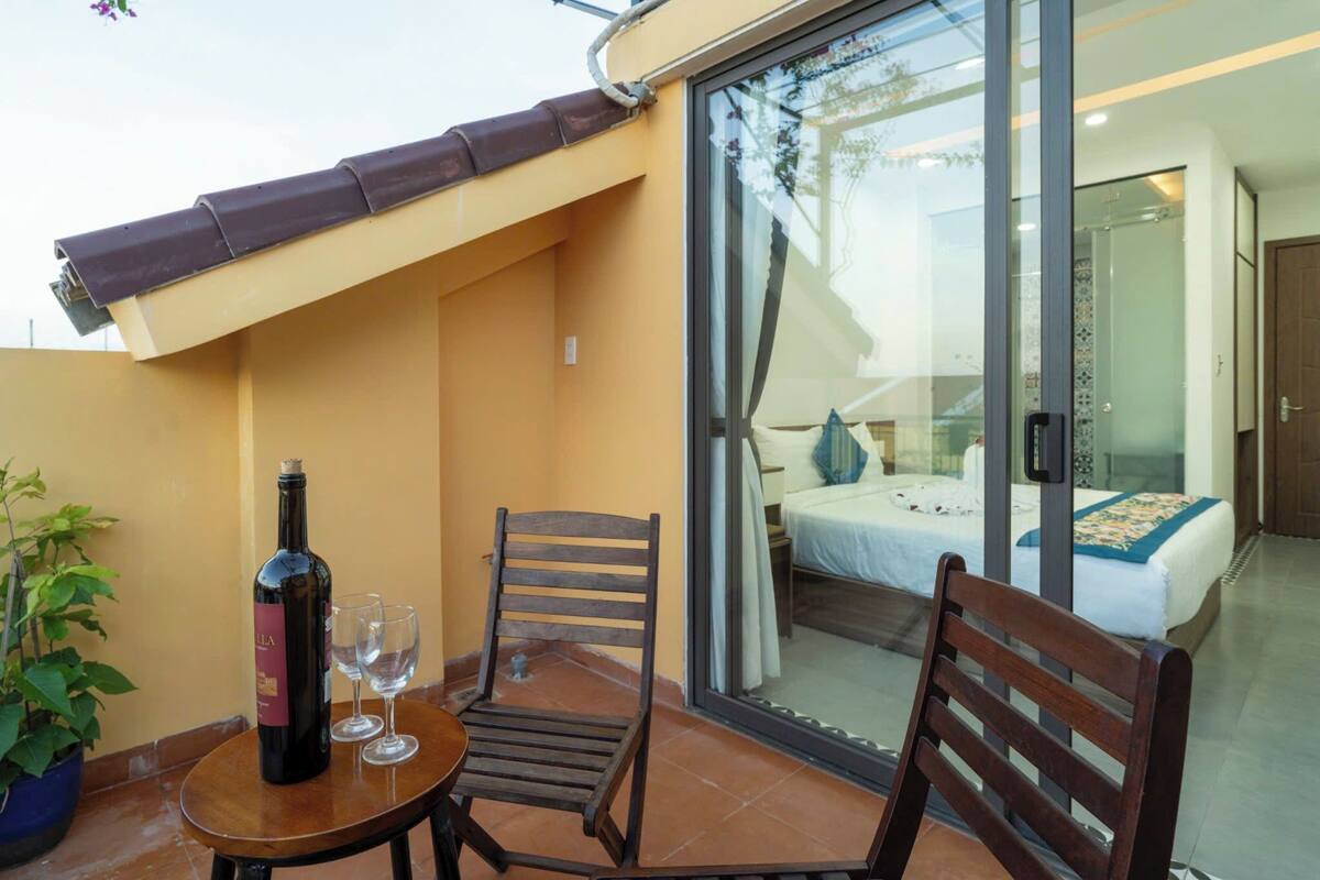 A balcony with a table, two chairs, a bottle of wine, and two glasses.