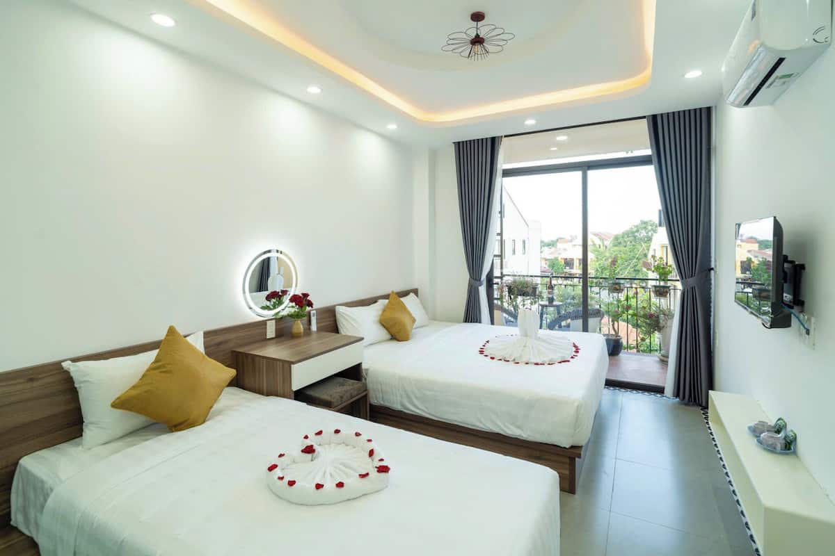 A hotel room with two beds, a desk, a mirror, a TV, and a balcony with a view.