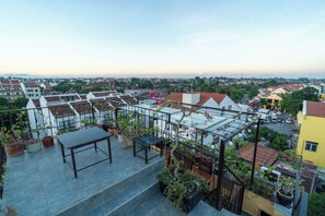 A rooftop terrace with a table and chairs, surrounded by potted plants and a railing. - Sweet Memories Villa - Hoi An (Da Nang)