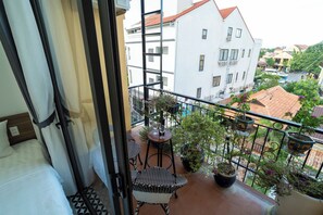 A balcony with a bed, a table, and potted plants. - Sweet Memories Villa - Hoi An (Da Nang)