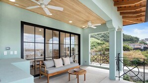 A modern living room with a sofa, coffee table, and large windows offering a view of the outdoors. - Sophisticated Modern Home w/ Ocean Views, Gorgeous Master Suites & Private Jacuzzi (Las Catalinas)