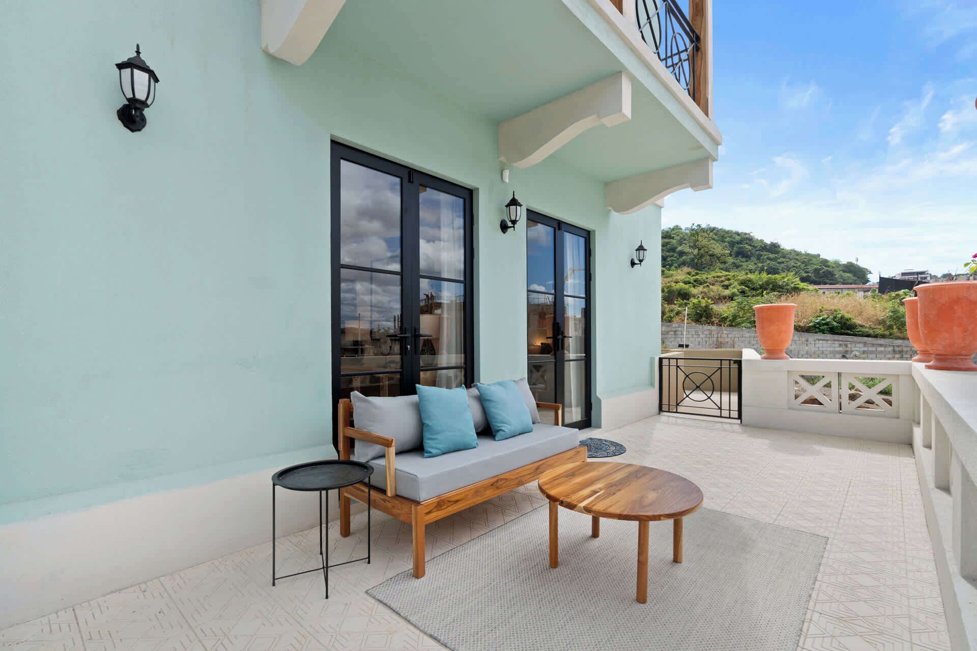 A balcony with a sofa, a small table, and a potted plant.
