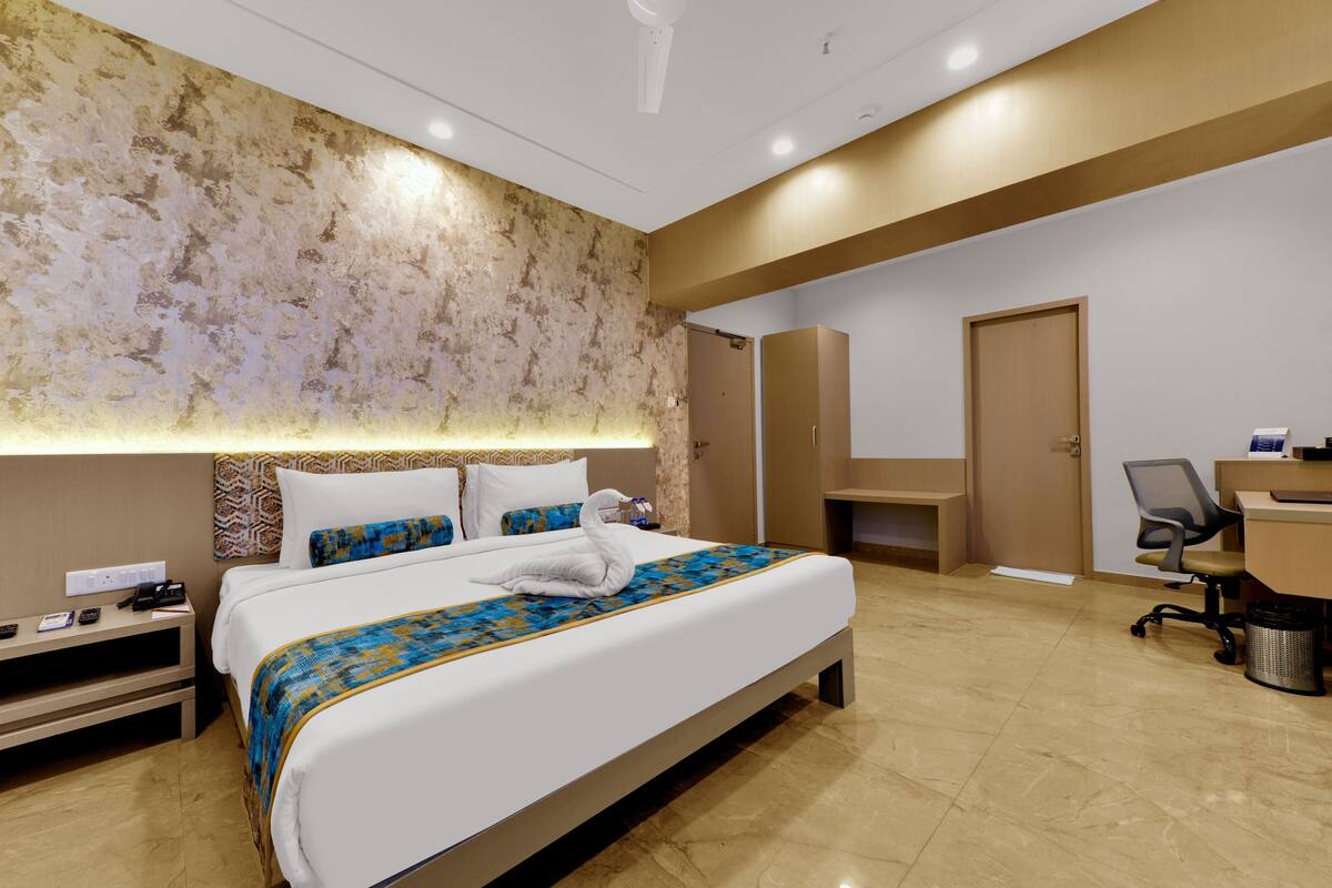 Een hotelkamer met een groot bed, een bureau met stoel, een kledingkast en een badkamer.