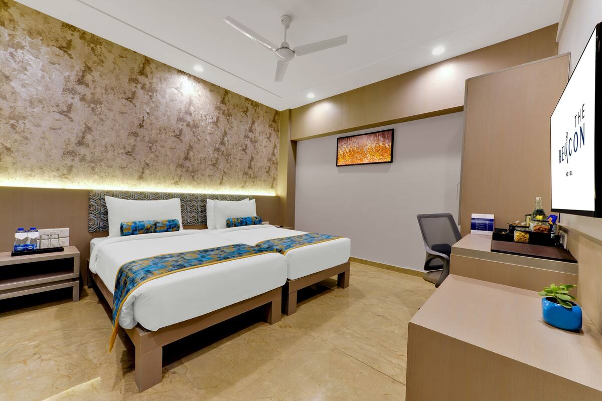 Een hotelkamer met een groot bed, een bureau, een stoel en een plafondventilator.