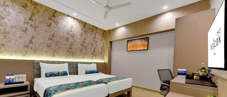 A hotel room with a large bed, a desk, a chair, and a ceiling fan.