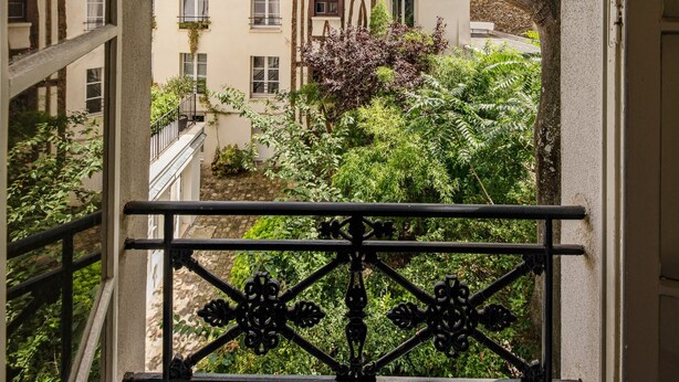 A balcony with a wrought iron railing overlooking a courtyard with buildings and trees. - Lovely 1BR in The Heart of Latin Quarter (Paris)