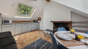 A kitchen with a skylight, a fireplace, and a dining area with a table set for two. - Lovely 1BR in The Heart of Latin Quarter (Paris)